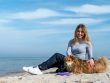 Woman enjoying a sunny day on Kołobrzeg beach with her dog, capturing the essence of leisure and companionship.