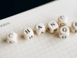 Close-up of letter dice spelling 'change' on a grid notepad, symbolizing transformation.