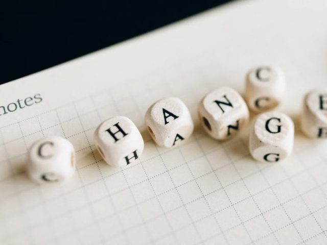 Close-up of letter dice spelling 'change' on a grid notepad, symbolizing transformation.